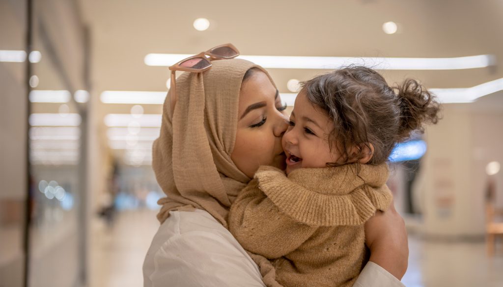 Mom and daughter cuddle in the airport